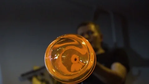 Glassblower in his workshop rotating rod with liquid glass. Close-up. Stock Footage 109718603