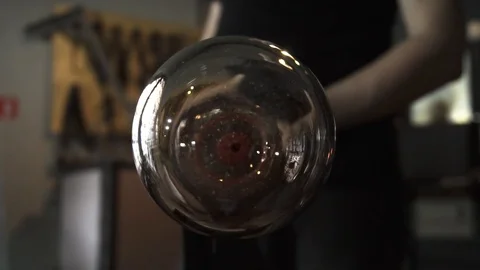 Glassblower in his workshop taking out rod with liquid glass and turning it Stock Footage 108990626
