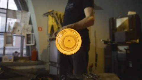 Glassblower in his workshop taking out rod with liquid glass and rotating it Stock Footage 108991326