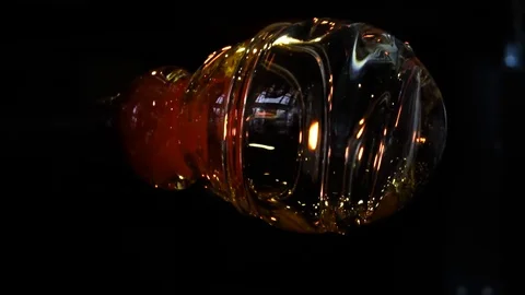 Glassblower in his workshop taking out rod with liquid glass and turning it Stock Footage 108991585