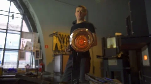 Glassblower in his workshop taking out rod with liquid glass and rotating it Stock Footage 109715020