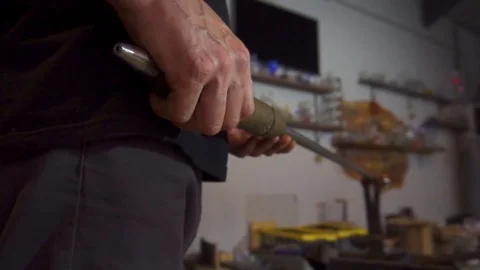 Glassblower in his workshop taking out rod with liquid glass and rotating it Stock Footage 109715500