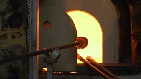 A glassblower or gaffer inserting melted hot glass into a traditional furnace. Stock Footage