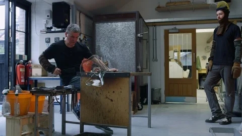 Glassblower shaping glassware in workshop Stock Footage 107936699