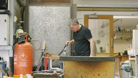 Glassblower using fire torch to shape glass Stock Footage 107890516