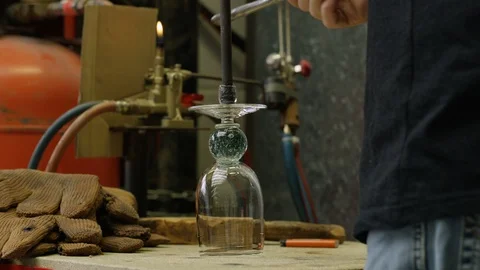 Glassblower using a fire touch while making a wine glass Stock Footage 107892894