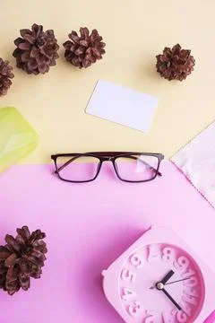 Glasses, alarm clock, pine tree flowers on a pastel pink and pastel yellow ba Stock Photos