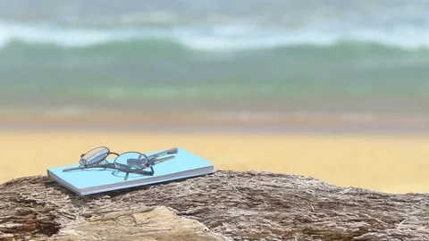 Glasses and notebooks are placed on notebooks beach plate. 库存影片 77553270