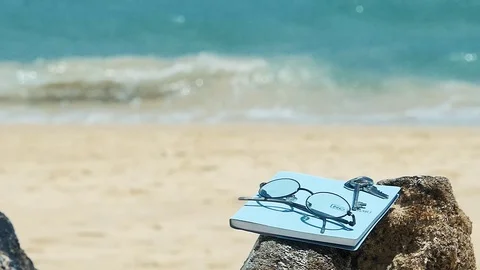 Glasses and notebooks are placed on notebooks beach plate. 库存影片 77559041