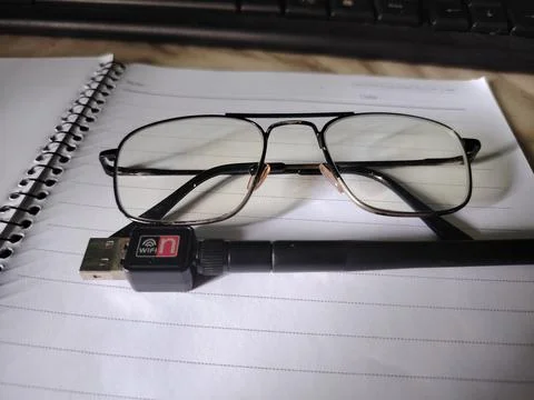 Glasses and wireless USB adapter on spiral notebook and keyboard  office su.. 스톡 사진
