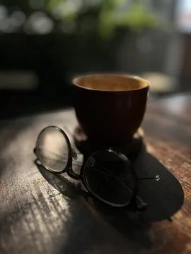 Glasses are placed on the table near a cup of coffee latte that has been drunk. Stock Photos
