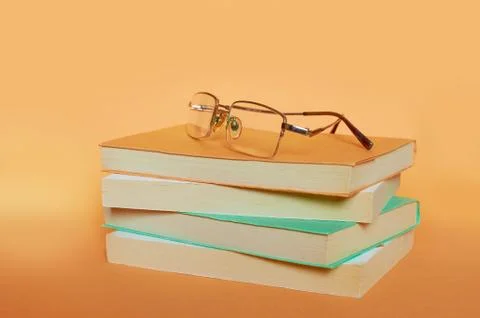 The glasses are on a stack of four books on a uniform background Stock Photos