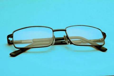 Glasses in a black frame on a blue background with copy space. World Day of Stock Photos