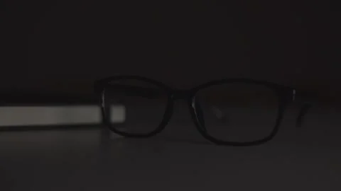 Glasses in a black frame lie on the table, changing light Stock Footage 244599361