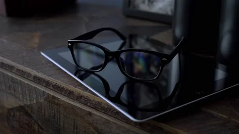 Glasses in black rim lying on a tablet on a wooden dresser in the room, close up Stock Footage 147937198