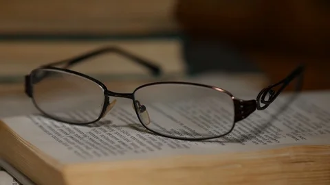 Glasses on the book highlighting with light Stock Footage 92961387