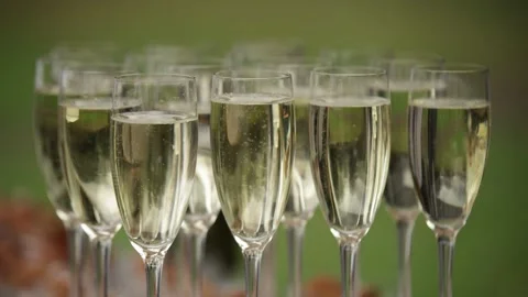 Glasses of Chablis wine stand on a background of green grass, bubbles rise insid Stock Footage 324564012