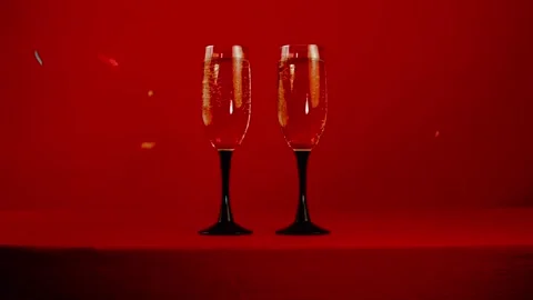 Glasses with champagne on a red background with confetti Stock Footage 85699586
