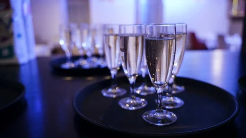 Glasses of champagne on a table in blue light. Champagne bubbles Stock Footage 125756984