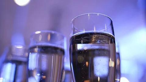 Glasses of champagne on a table in blue light. Champagne bubbles Stock Footage 125757038
