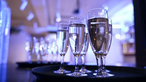 Glasses of champagne on a table in blue light. Champagne bubbles Stock Footage 125757072