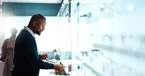 Glasses, choice and optometry with man in store for prescription, eye care or Stock Photos