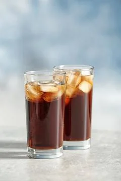 Glasses of cold cola on table against color background. Space for text Fotos Stock