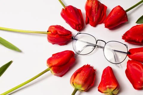 Glasses, eyeglasses in black, thin frames with red tulips, on a light backg.. Stock Photos