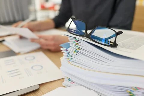 Glasses for eyesight lie on stack of documents at workplace Stock Photos