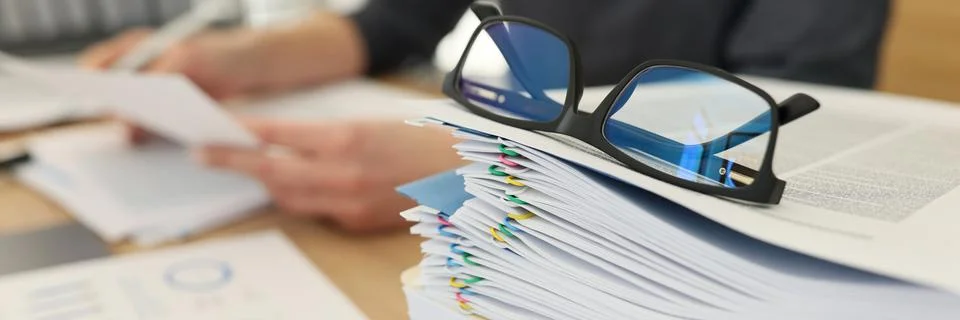 Glasses for eyesight lie on stack of documents at workplace Stock Photos