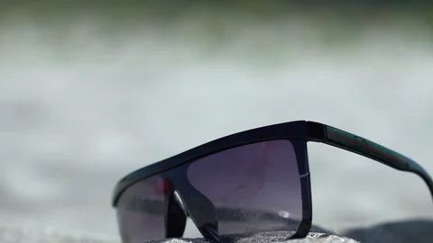 Glasses fall into the sand. in reflection lifeguard running towards the sea Stock Footage 125990523