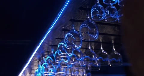 Glasses hang on top of the bar and are illuminated in blue light. High quality Stock Footage 221786534