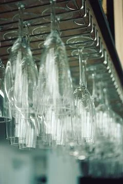 Glasses hanging upside down in  bar setting during evening hours. Several cle Stock Photos