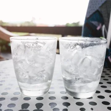 Glasses with ice cubes on black dot background table Stock Photos