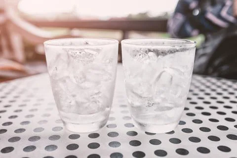 Glasses with ice cubes on black dot background table Stock Photos