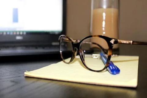 Glasses infront of computer on top of writting pad Stock Photos