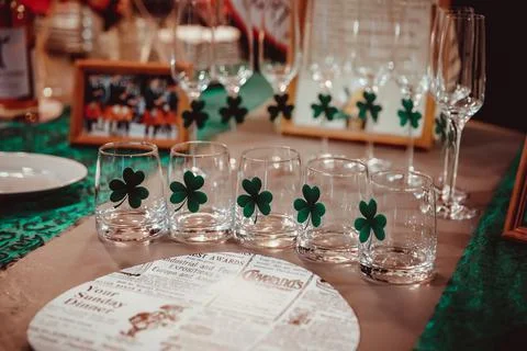 Glasses with irish clover on the table Stock Photos