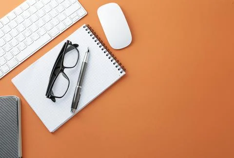 Glasses keyboard mouse pen notepad and diary on orange background Stock Photos
