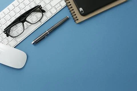 Glasses keyboard notepad mouse pen and phone on blue background Stock Photos
