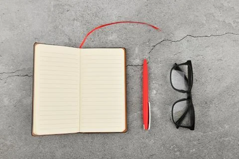 Glasses with notebook on gray background. Office desk with business accessori Foto stock