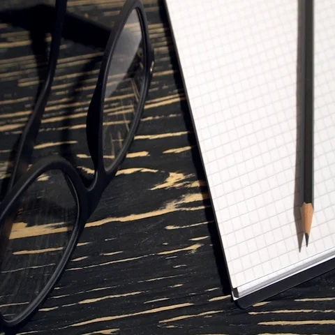 Glasses, pencil and notebook on black wooden background. Stock Footage 69285226