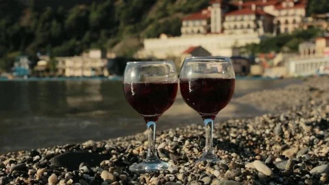 Glasses of red wine on the beach on the background of a luxury hotel Stock Footage 82336934