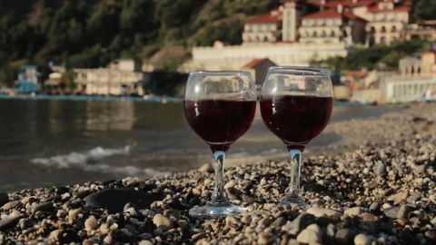 Glasses of red wine on the beach on the background of a luxury hotel Stock Footage 82337478