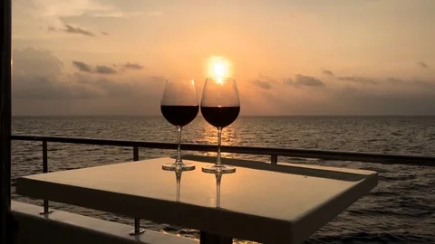 Glasses with red wine on yacht with tropical sunset Stock Footage