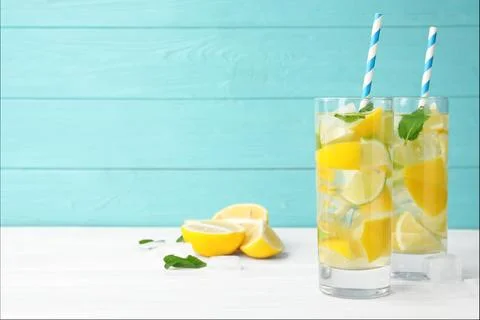 Glasses of refreshing lemonade on table against light blue wooden background, Stock Photos