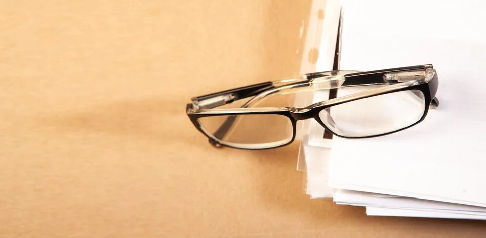 Glasses on a stack of papers on a wooden background. Business concept Stock Photos