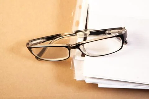 Glasses on a stack of papers on a wooden background. Business concept Stock Photos