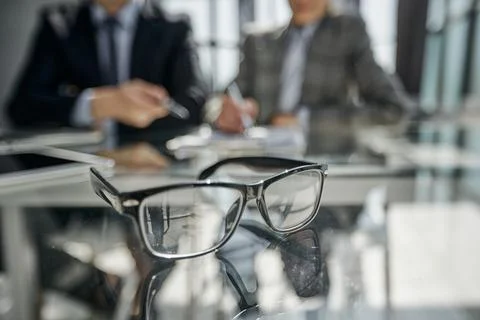 Glasses on the table in the office on a blurred background of colleagues Photos