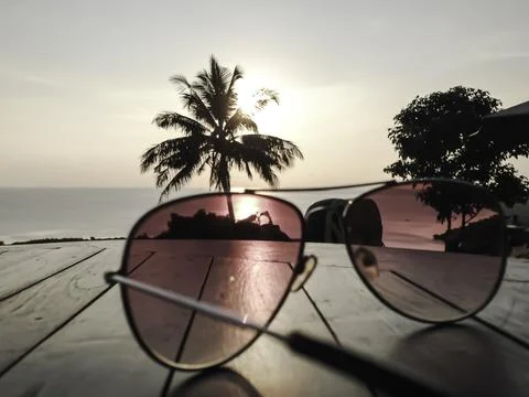 Glasses on table. Palm tree and sunset Stock Photos