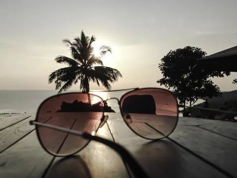 Glasses on table. Palm tree and sunset Stock Photos